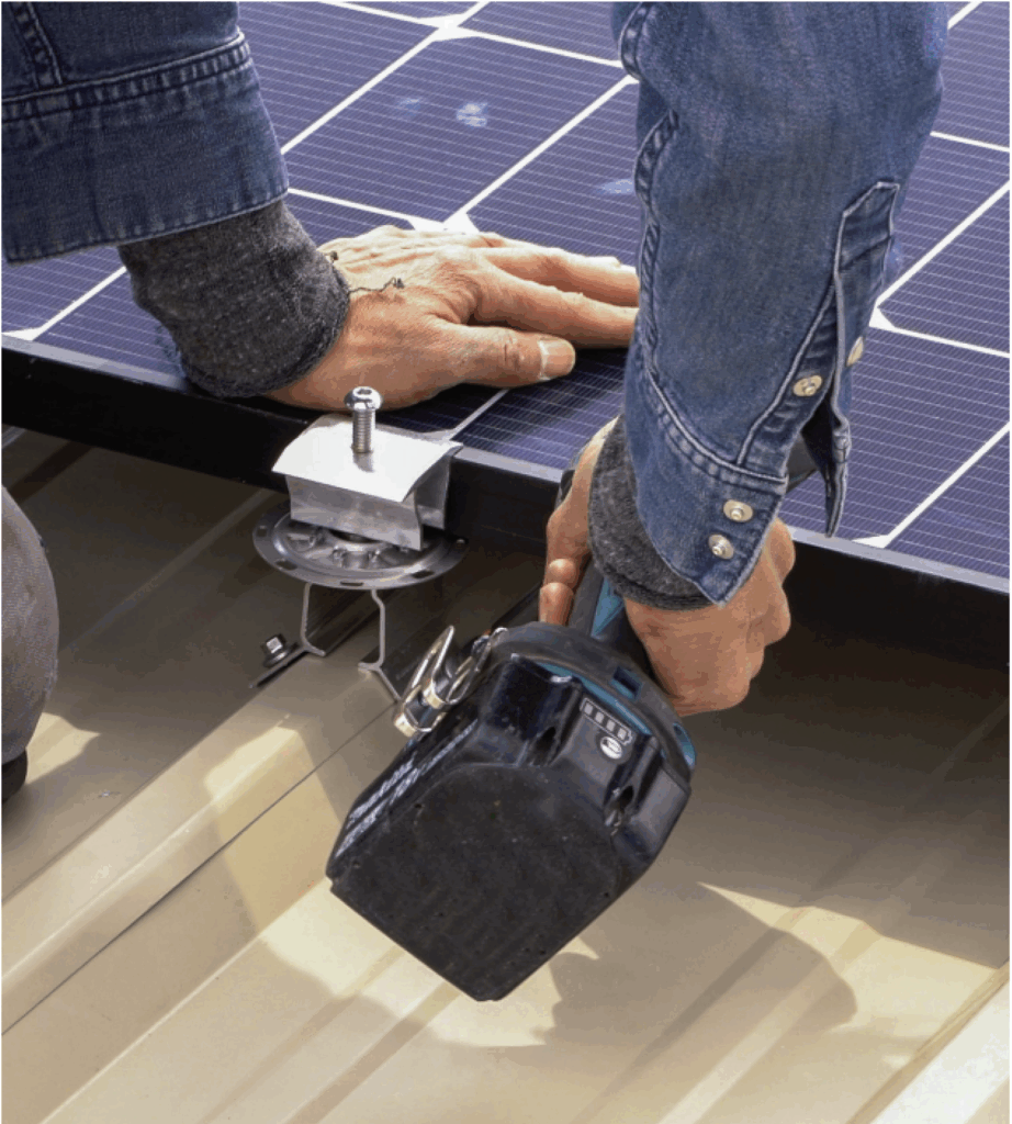 A man securing a solar panel using a screw gun to install PVKIT with RibBracket I-V.